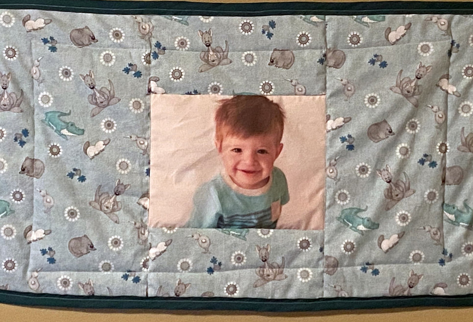 A quilt featuring a picture of a young child in the center
